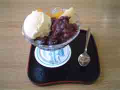 pciture of anmitsu, boiled red beans, agar cubes, ice cream and sweeted syrup.